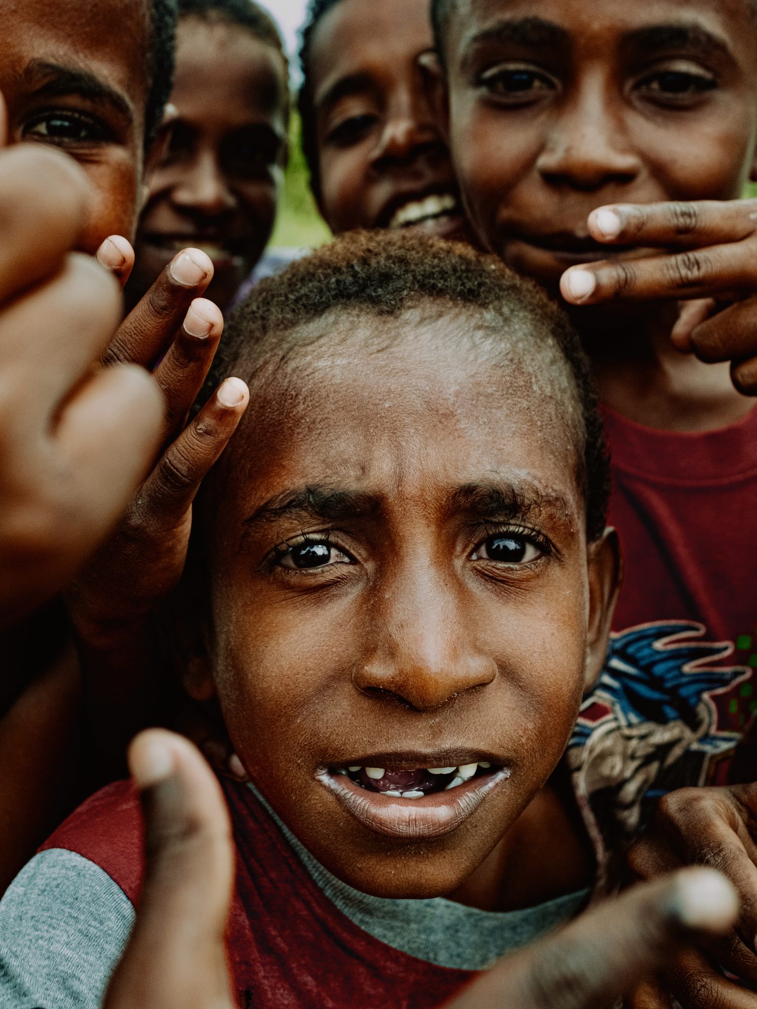 A close portrait of a boy grinning among his friends
